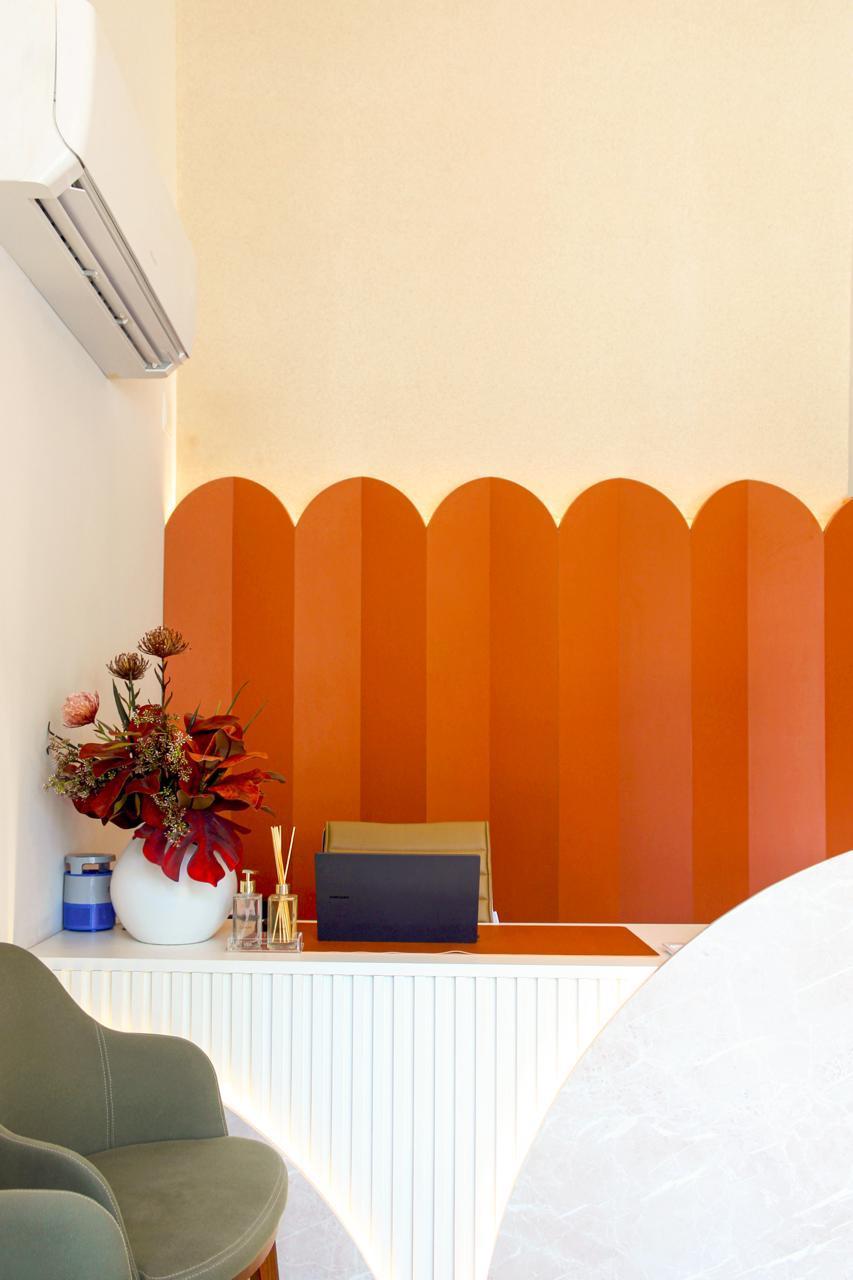 Detalhe do balcão de recepção com painel ondulado terracota — Edna Designer