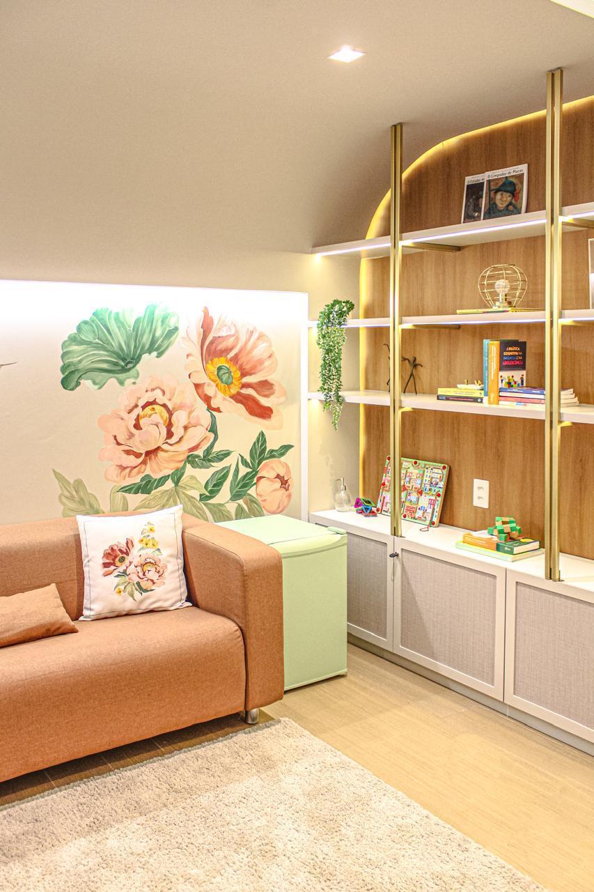 Espaço kids com estante, sofá terracota e mural floral — Edna Designer