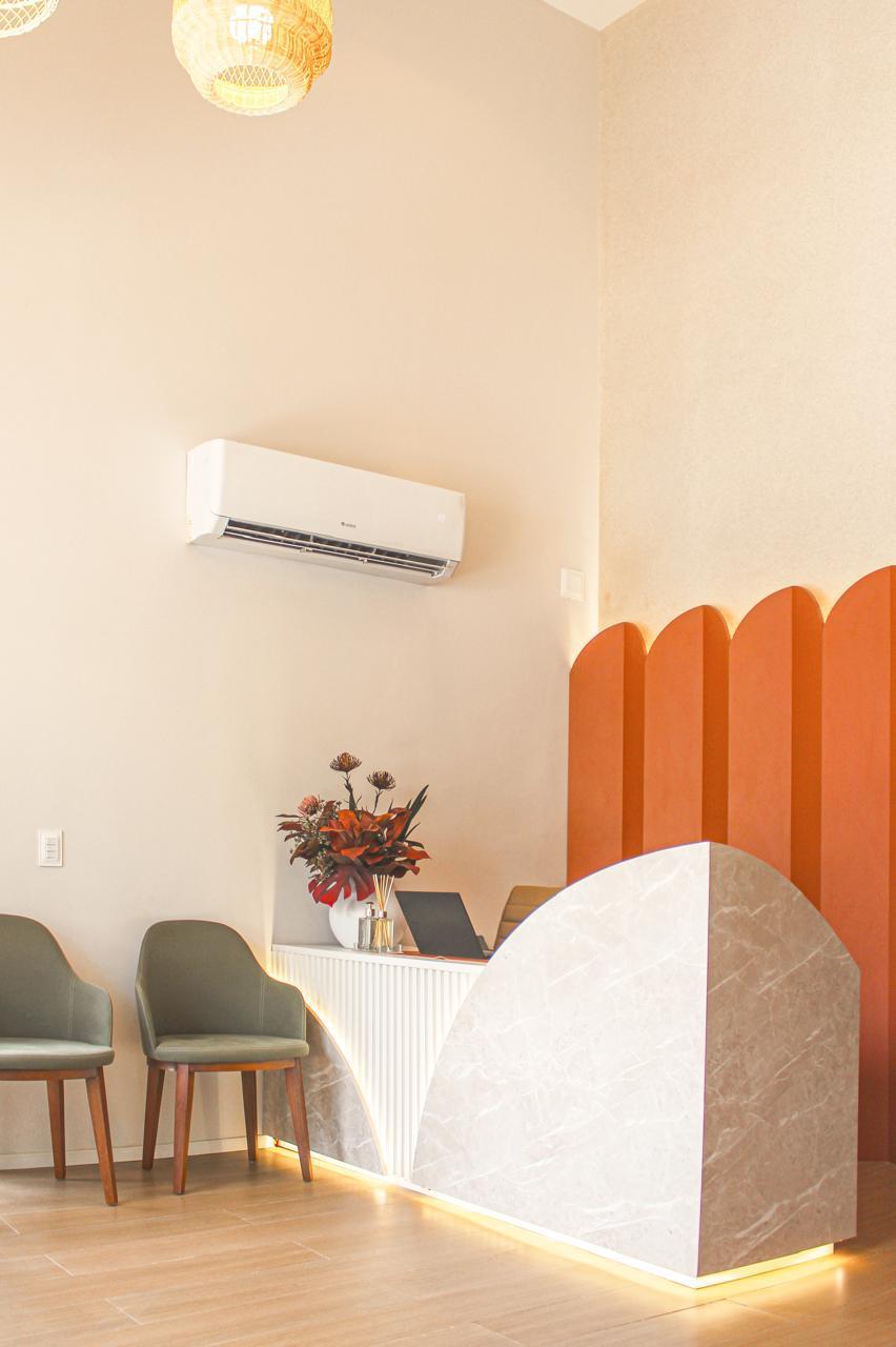 Recepção com balcão de mármore, painel ondulado e poltronas verdes — Edna Designer