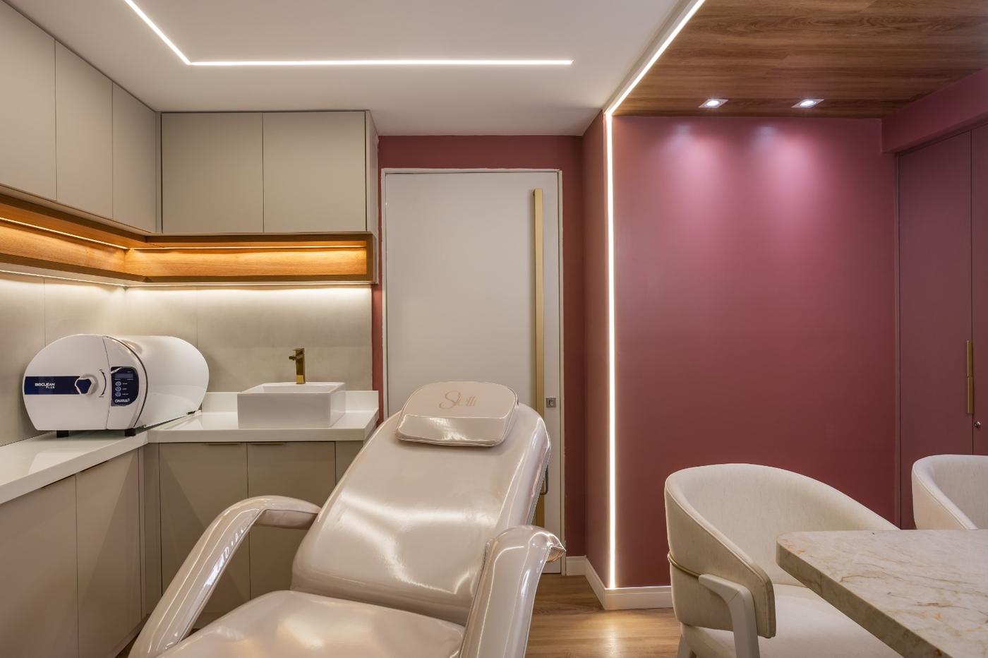 Sala de procedimento com maca reclinável e parede rosé iluminada — Edna Designer