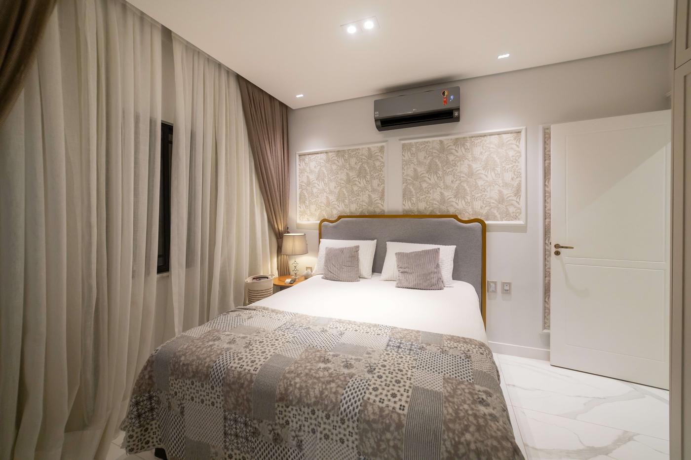 Dormitório com cabeceira estofada, cortinas e painéis florais — Edna Designer