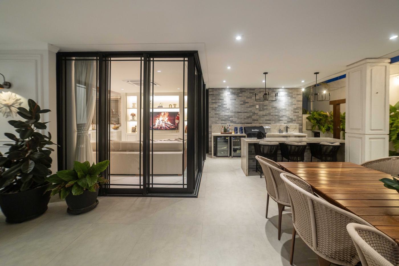 Área gourmet integrada com bancada, adega e espaço de convivência — Edna Designer