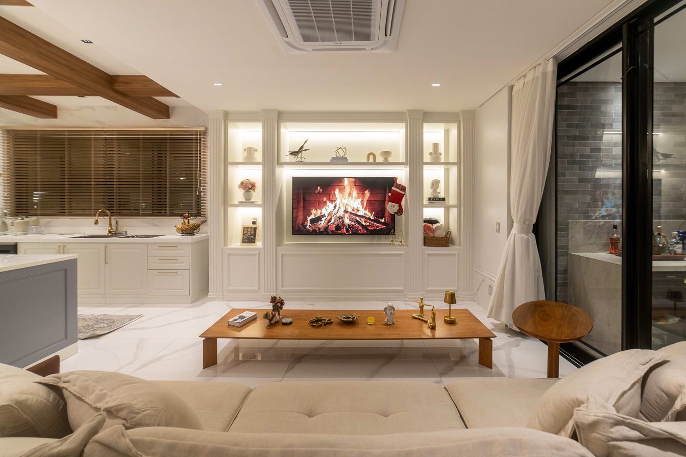 Sala de estar com painel de TV, lareira decorativa e estante iluminada — Edna Designer